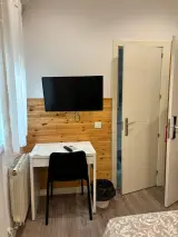 Aire acondicionado sobre la ventana, televisor y escritorio con silla en la habitación